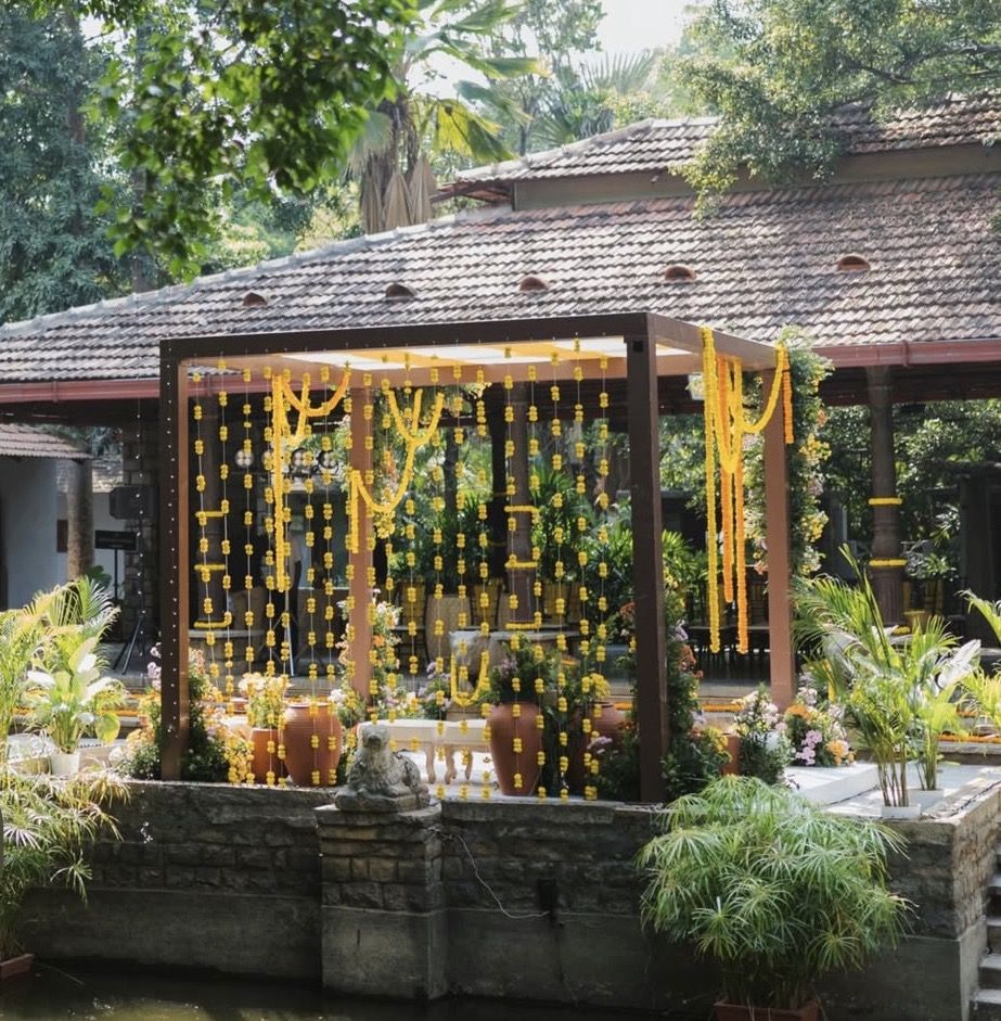 Garden pergola hung with marigold strings and terracotta pots for a haldi ceremony